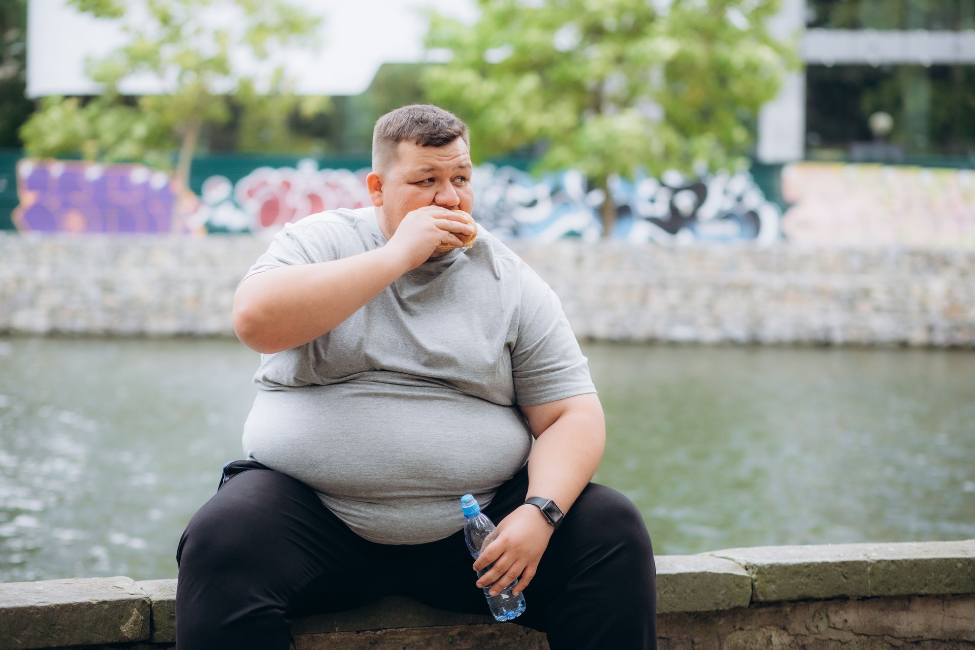 a very fat man is eating a burger